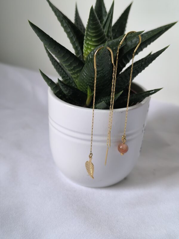 Boucle d'oreille chaine en pierre du soleil, et une breloque feuille sur l'autre. créées par Main de Crystal.