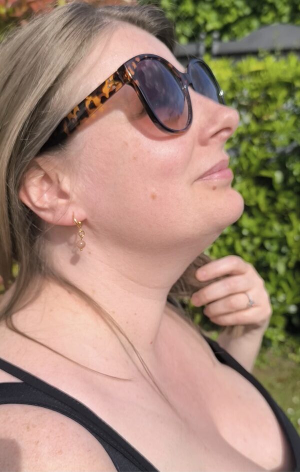 Femme portant des boucles d'oreilles minis créoles en pierre du soleil, créées par maindecrystal